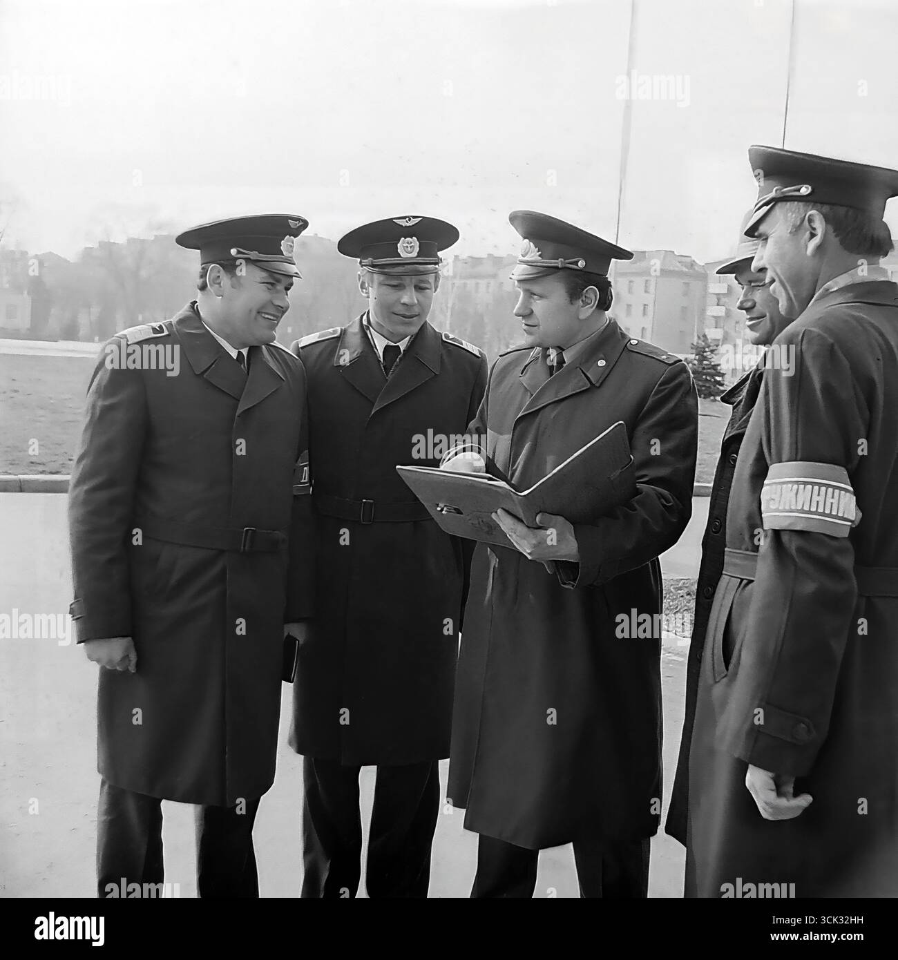 Der Leiter des Freiwilligen Zentrums der Volksdruschina (DND) führt in den 1980er Jahren ein Briefing oder eine Rosterkontrolle mit einer Patrouillengruppe auf einem Platz in Slowiansk, ukrainische SSR, durch Das Archivfoto zeigt ein gemischtes Team der Druzhina, darunter Angestellte in Uniformen der Abteilung und Freiwillige, von denen einer das charakteristische „Druzhinnik“-Armband trägt. Diese Szene spiegelt den organisierten Charakter der Arbeit der DND bei der Aufrechterhaltung der öffentlichen Ordnung in sowjetischen Städten und den Geist der kollektiven Verantwortung wider Stockfoto