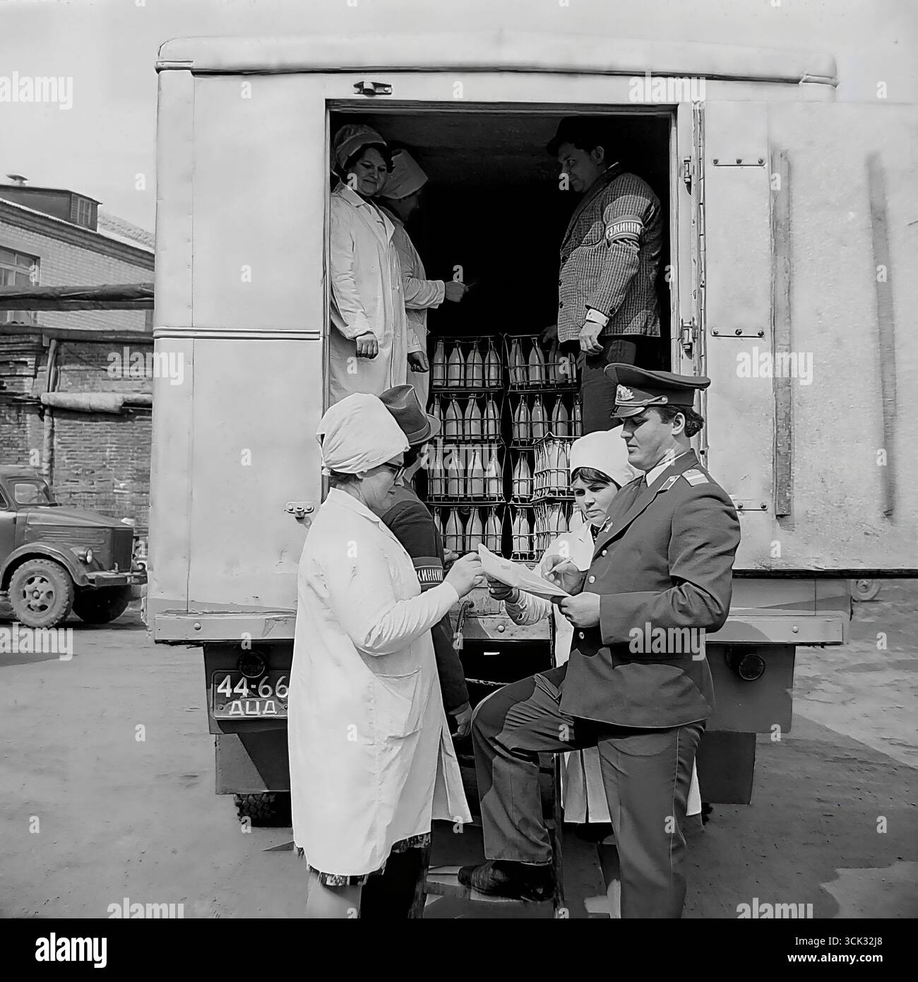 Ein Angriff gegen den Diebstahl sozialistischer Grundstücke in Sloviansk, der ukrainischen SSR, in den 1980er Jahren Das Archivfoto zeigt einen Militsiya-Offizier und einen Druzhinnik (Mitglied der Volkspatrouille), der Dokumente für eine Lieferung von Milchprodukten mit weiblichen Arbeitern aus einem Milchbetrieb überprüft. Diese Szene ist ein eindrucksvolles Dokument der späten UdSSR-Ära, das die Versuche des Staates widerspiegelt, den Warenfluss zu kontrollieren und mit Hilfe von Strafverfolgungsbehörden und der Öffentlichkeit gegen Diebstahl zu kämpfen (DND). Stockfoto