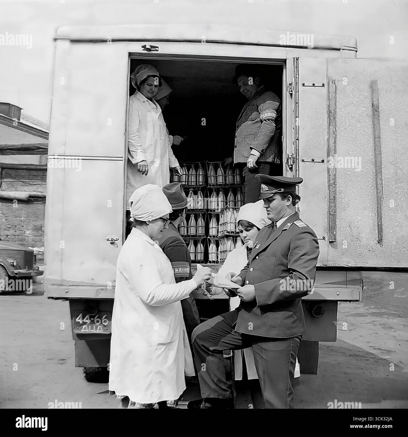 Ein Angriff gegen den Diebstahl sozialistischer Grundstücke in Sloviansk, der ukrainischen SSR, in den 1980er Jahren Das Archivfoto zeigt einen Militsiya-Offizier und einen Druzhinnik (Mitglied der Volkspatrouille), der Dokumente für eine Lieferung von Milchprodukten mit weiblichen Arbeitern aus einem Milchbetrieb überprüft. Diese Szene ist ein eindrucksvolles Dokument der späten UdSSR-Ära, das die Versuche des Staates widerspiegelt, den Warenfluss zu kontrollieren und mit Hilfe von Strafverfolgungsbehörden und der Öffentlichkeit gegen Diebstahl zu kämpfen (DND). Stockfoto