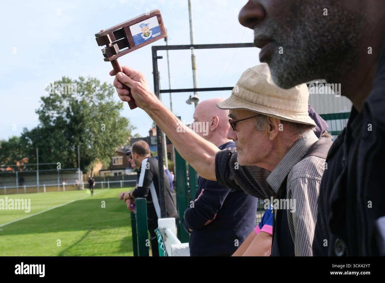 Ein alternder Fußballfan mit altmodischer Fußballrassel bejubelt Walthamstow FC während des Spiels der FA Trophy gegen Downham Town Stockfoto