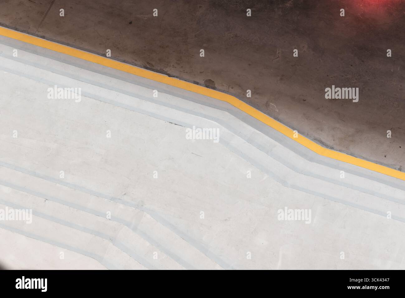 Abstraktes minimalistisches Bild mit einer Betontreppe mit einer gelben Trennlinie und Schatten, die eine moderne und geometrische Ästhetik bietet, ideal für Desigers Stockfoto