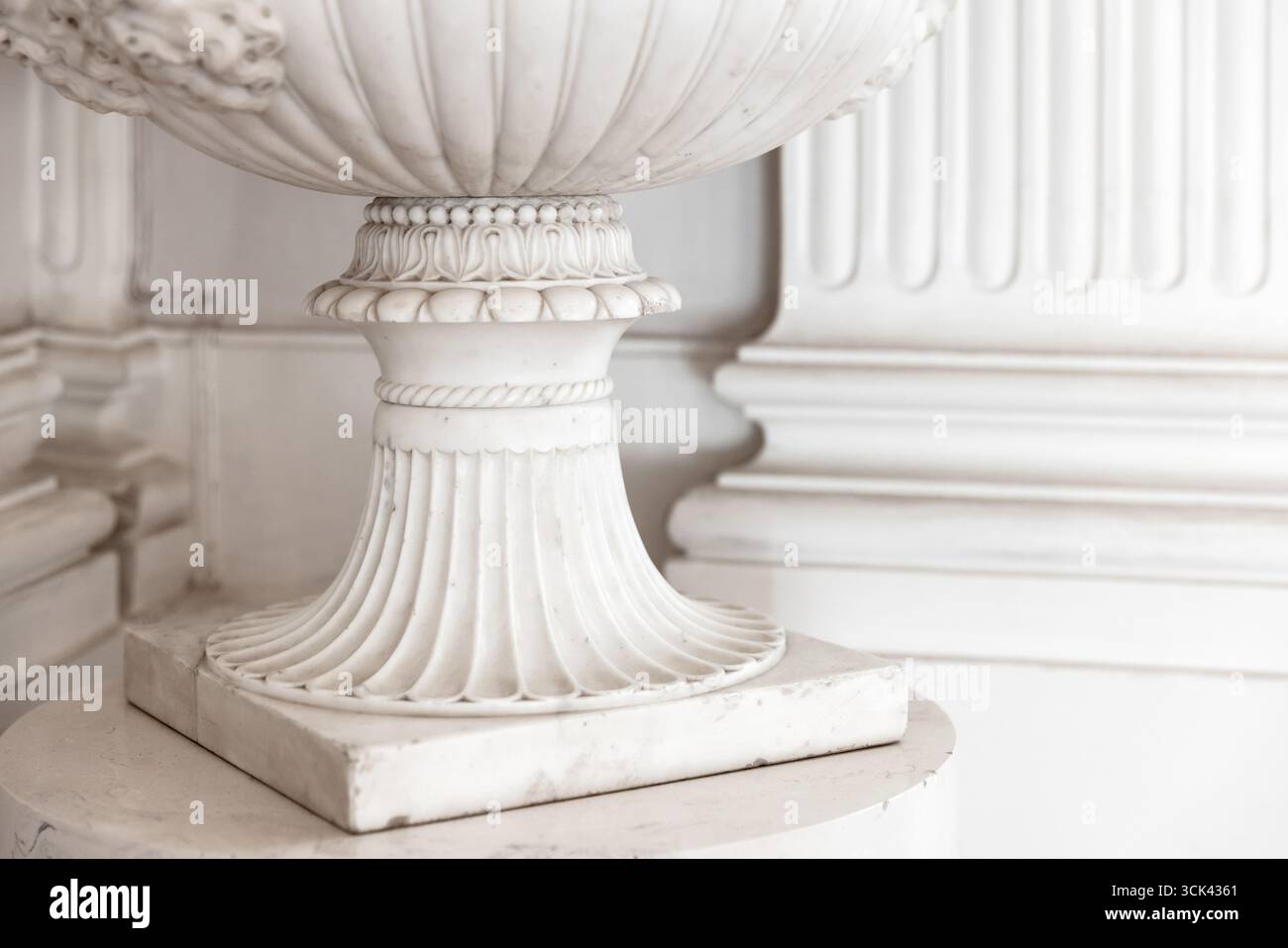 Eleganter Sockel aus weißem Stein mit komplexen Details und klassischem Design, der zeitlose Raffinesse und anmutige Handwerkskunst ausstrahlt. Archit Stockfoto
