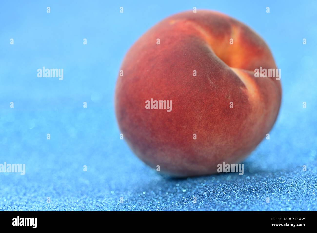 Frischer Pfirsich auf funkelndem blauem Hintergrund Stockfoto