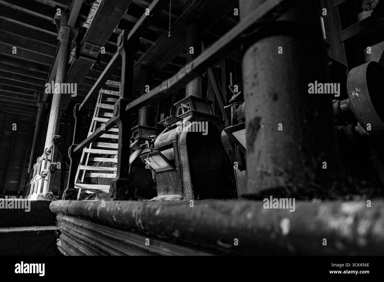 Rostende Maschinen befinden sich in einem schwach beleuchteten verlassenen Lagerhaus, was eine Mischung aus Geschichte und Vernachlässigung hervorhebt. Stockfoto