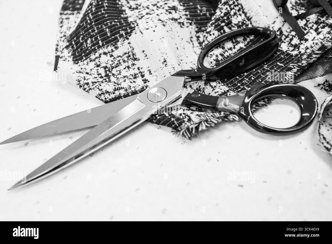 Nahaufnahme von Stoff und Schere im Designstudio, schwarz-weiß Stockfoto