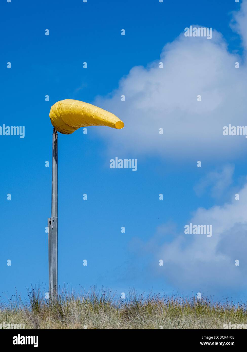 Gelbe Windsocke, die bei starkem Wind gegen den Himmel weht Stockfoto
