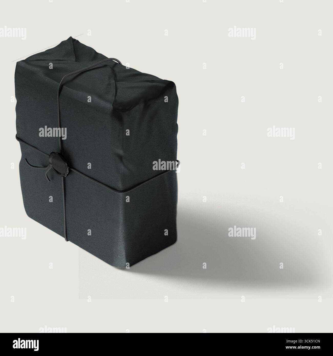 Ein sorgfältig umhülltes schwarzes Paket, das mit einem Riemen gesichert ist und ein Geschenk oder ein Produkt vorschlägt, das zur Lieferung bereit ist. Stockfoto
