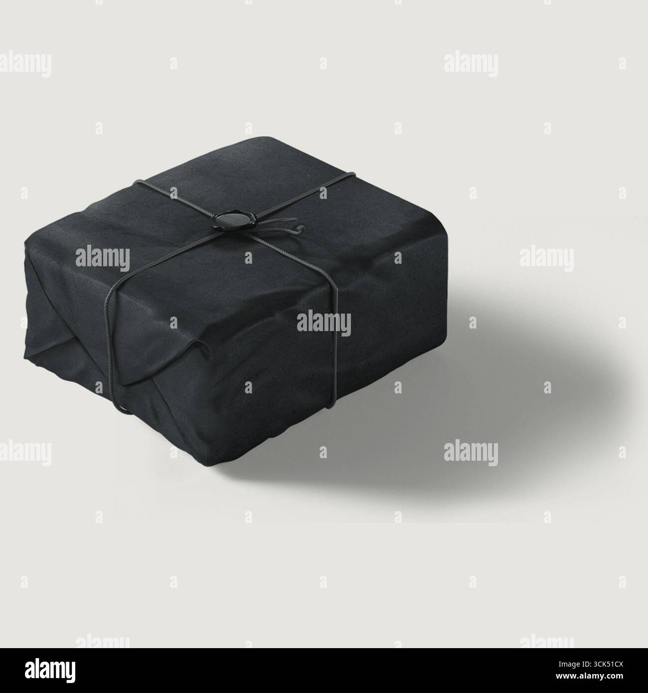 Ein ordentlich gewickeltes schwarzes Paket mit einer Schnur, das einen subtilen Schatten wirft. Stockfoto