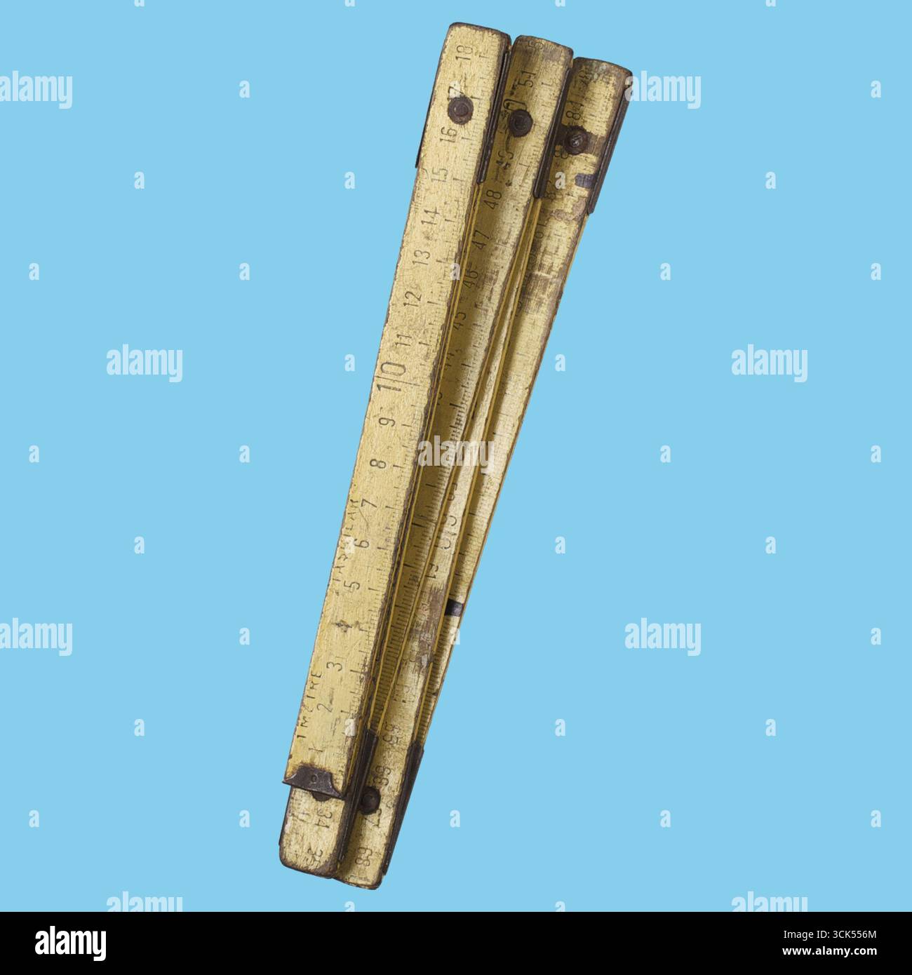 Ein faltendes Lineal im Vintage-Stil mit Abmessungen, das Verschleiß und Alter angibt und für präzise Messungen bei verschiedenen Aufgaben verwendet wird. Stockfoto