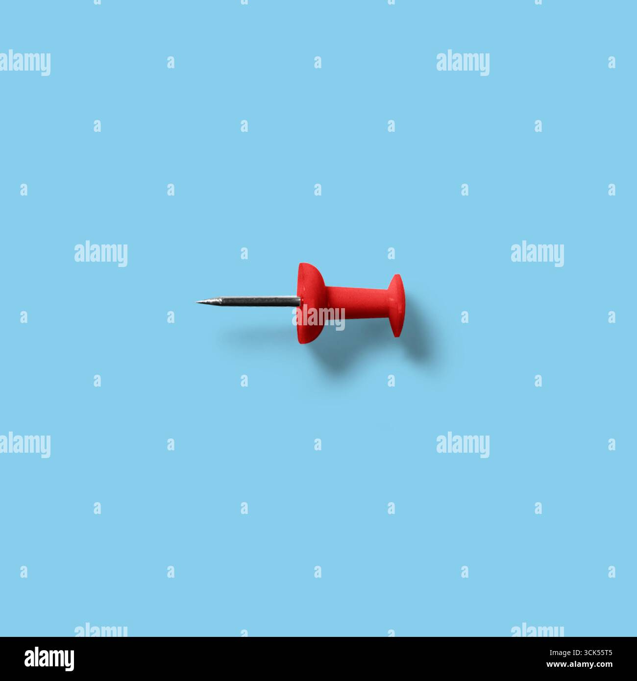 Ein roter Druckstift mit einer Metallspitze, der häufig zum Anheften von Papieren oder Notizen an Pinnwände verwendet wird. Stockfoto