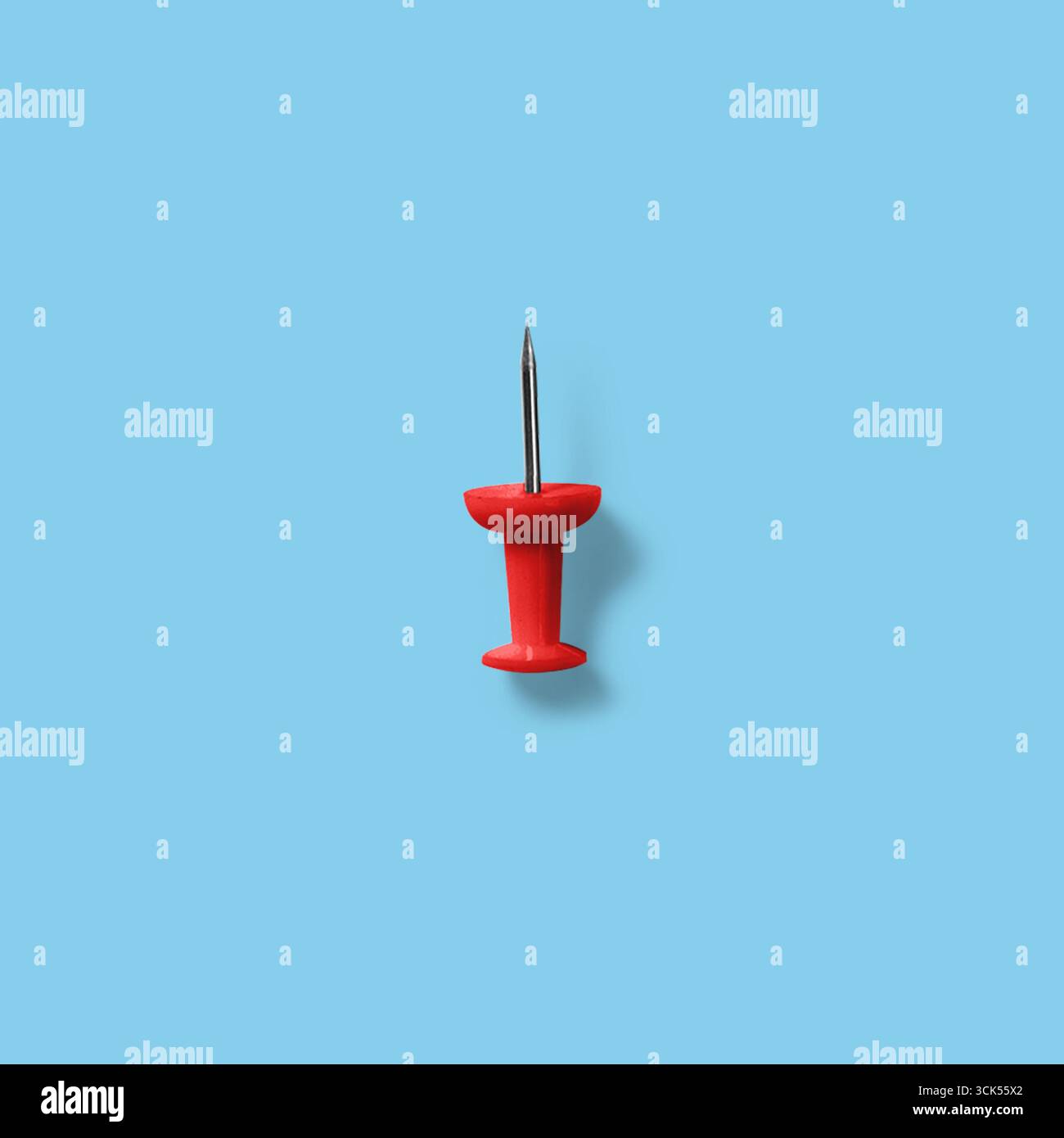 Ein roter Druckstift mit einer Metallspitze, der häufig zum Anheften von Notizen oder Papieren an Pinnwände verwendet wird. Stockfoto