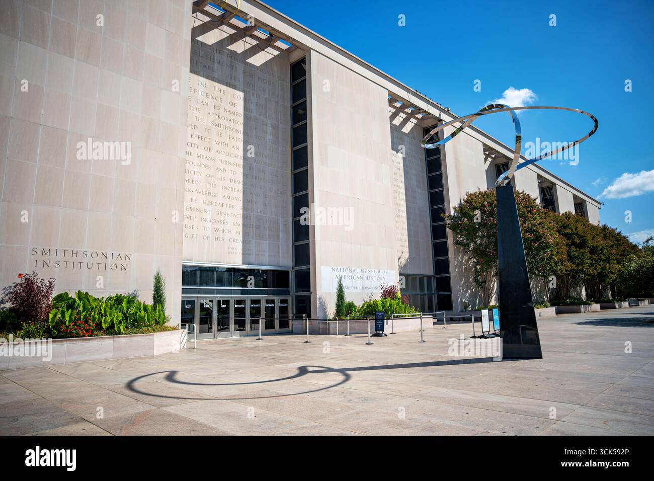 National Museum of American History Infinity Sculpture Washington DC // WASHINGTON DC – das National Museum of American History, offiziell bekannt als Kenneth E. Behring Center, ist mit seinem Eingang zur National Mall und der Infinity Skulptur zu sehen. Das Museum ist eine prominente Institution, die sich der Erhaltung und Präsentation der reichen Geschichte des Landes widmet. Die Fassade ist mit Text aus John Quincy Adams' Charta für die Smithsonian Institution versehen, was ihren grundlegenden Zweck widerspiegelt. Die Infinity-Skulptur, ein modernes künstlerisches Element, steht im Gegensatz zur klassischen Architektur des Buils Stockfoto