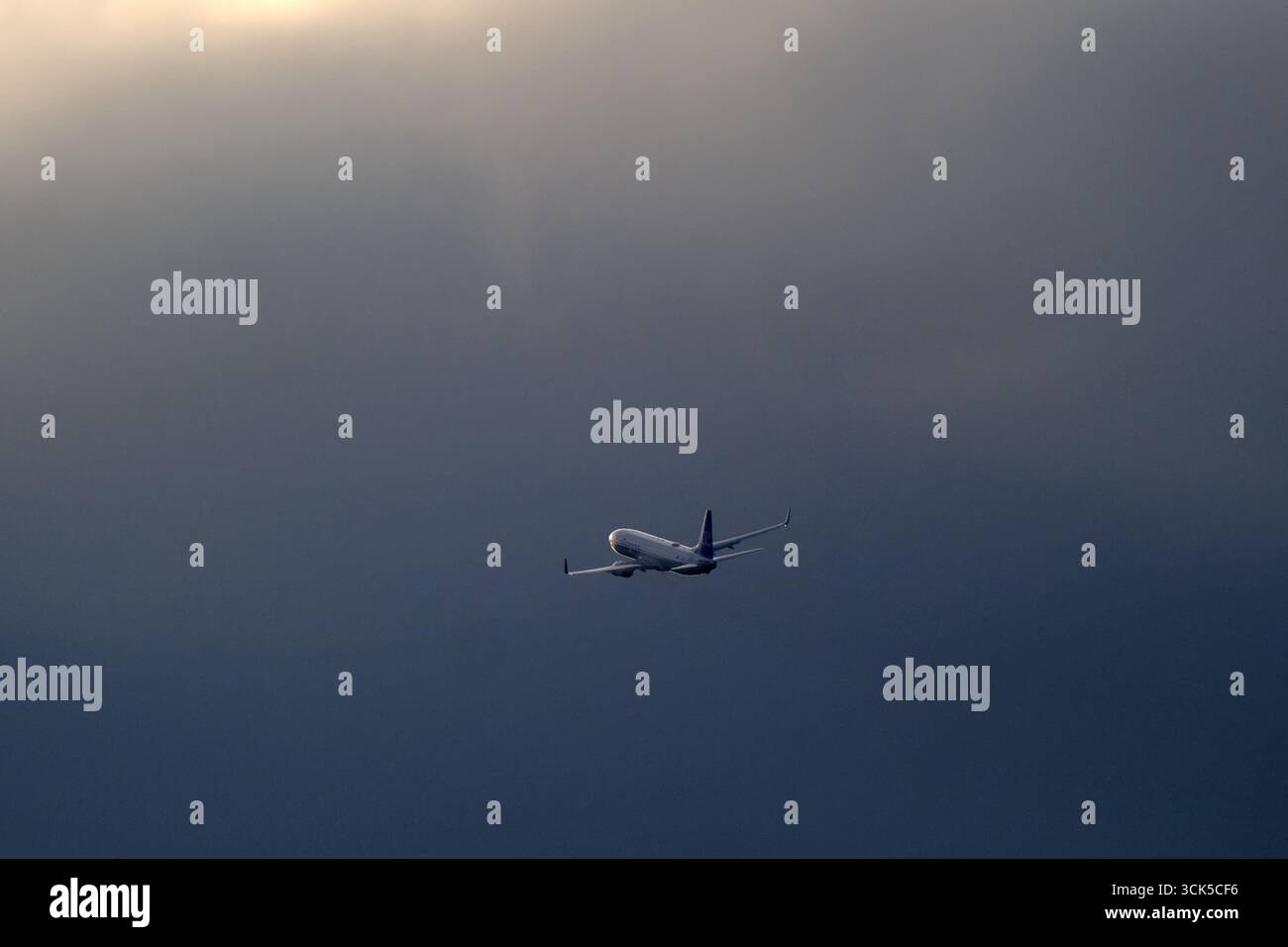 Flugzeuge am Flughafen Zürich - ein Flugzeug startete vom Flughafen Zürich, beleuchtet von der Sonne mit dunklen Wolken im Hintergrund Stockfoto