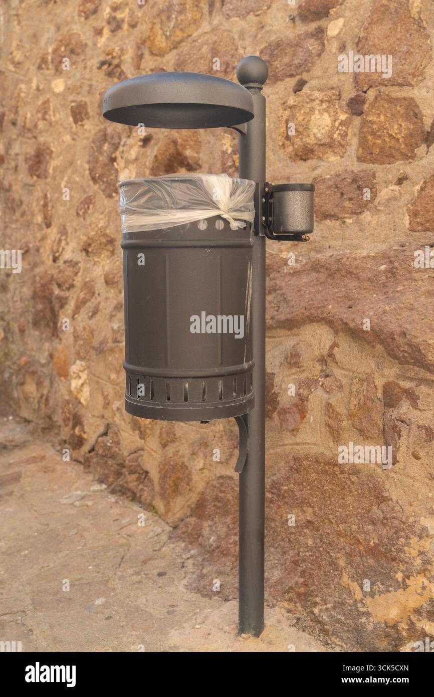 Städtischer Abfallbehälter mit Kunststoffauskleidung gegen eine strukturierte Steinwand. Das robuste Design und die praktische Platzierung machen ihn ideal für die Wartung Stockfoto