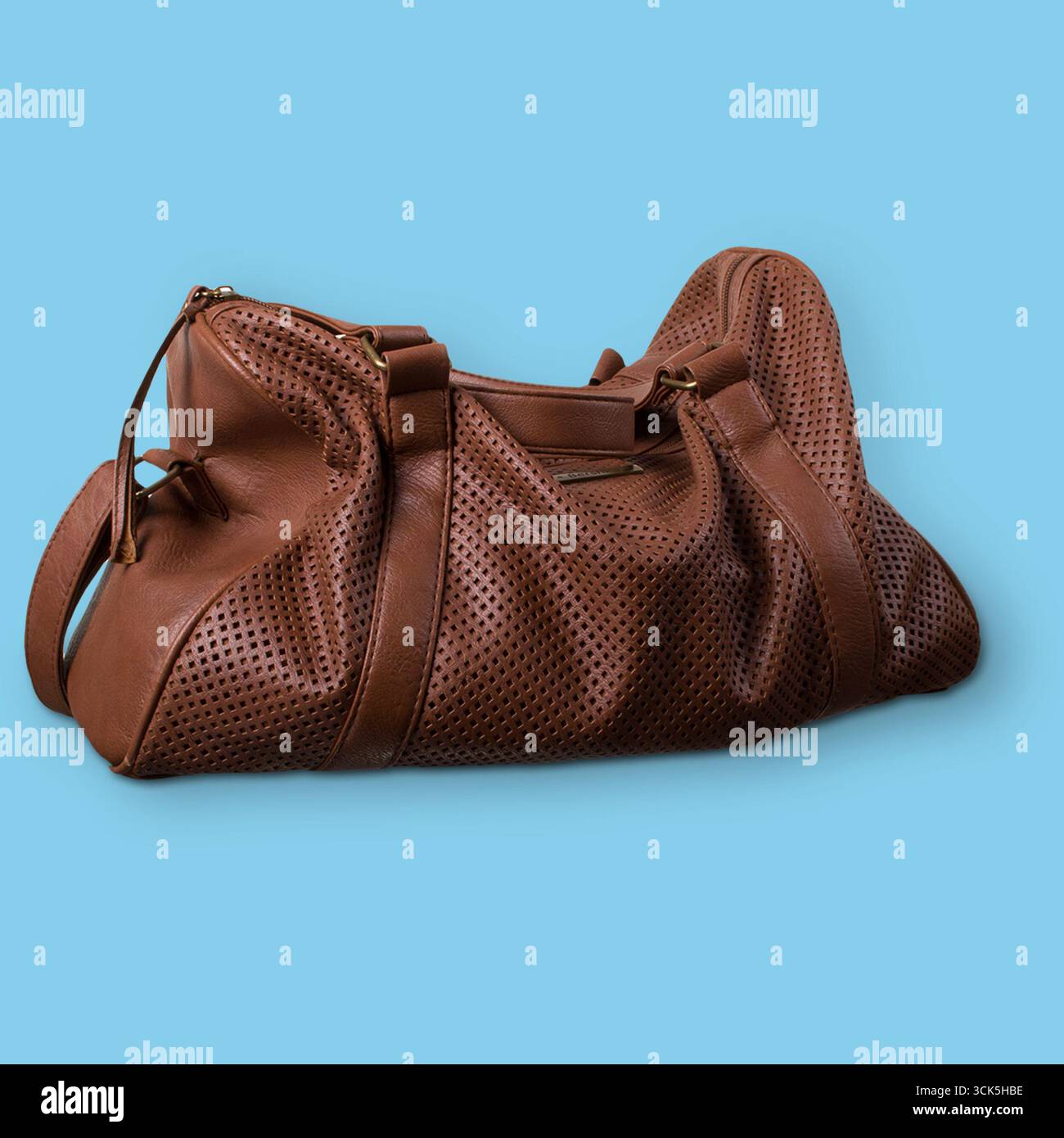 Eine stilvolle, braune Ledertasche mit perforiertem Design, geeignet für Reisen oder Fitnessstudio. Stockfoto