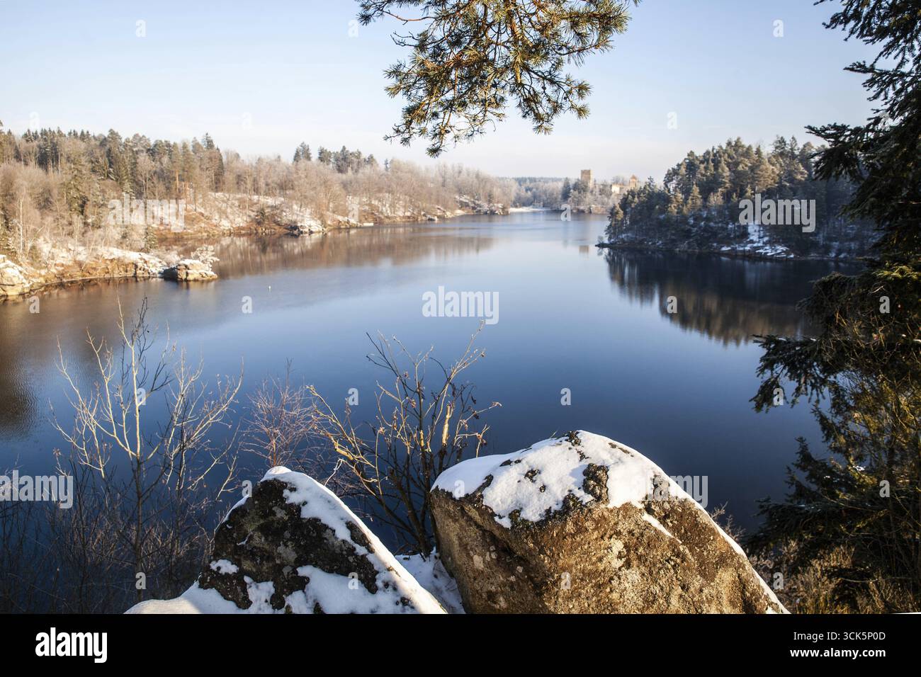 Ein schneebedeckter, ruhiger See mit umliegenden Bäumen und Felsen in winterlicher Atmosphäre Ottensteiner Stausee Waldviertel Niederösterreich Österreich Stockfoto