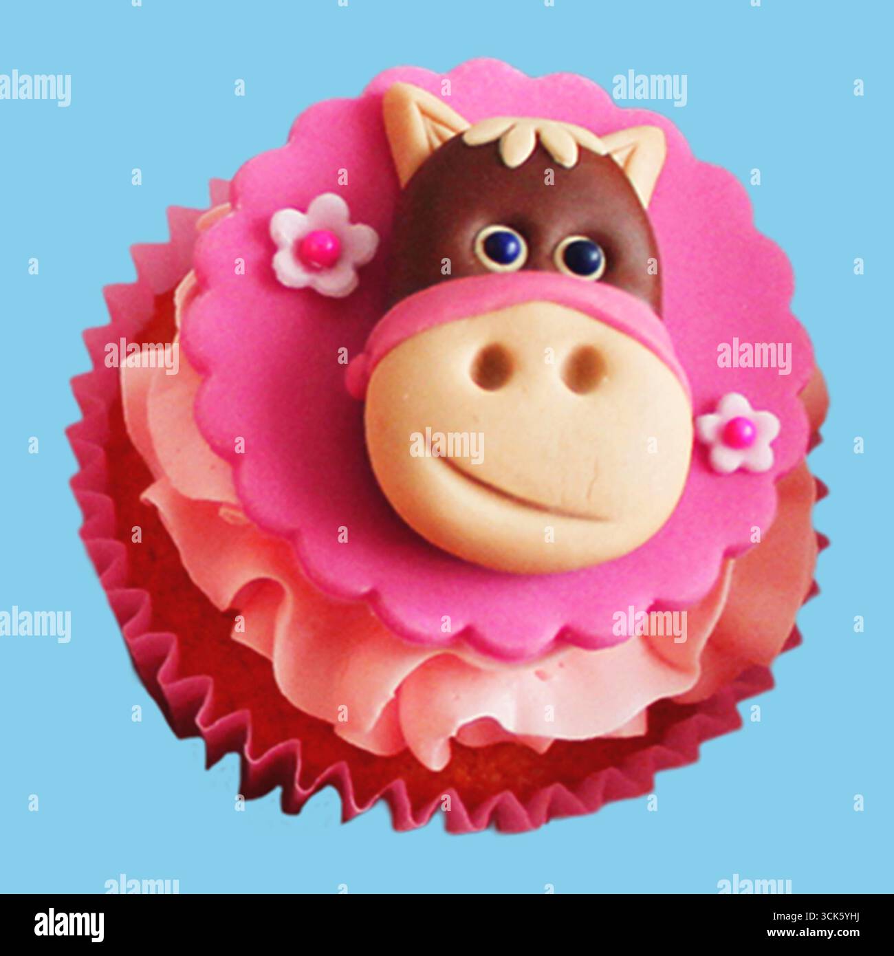 Ein skurriler Cupcake mit rosa Pferdegesicht aus Fondant, ideal für Kinderpartys oder Feiern. Stockfoto