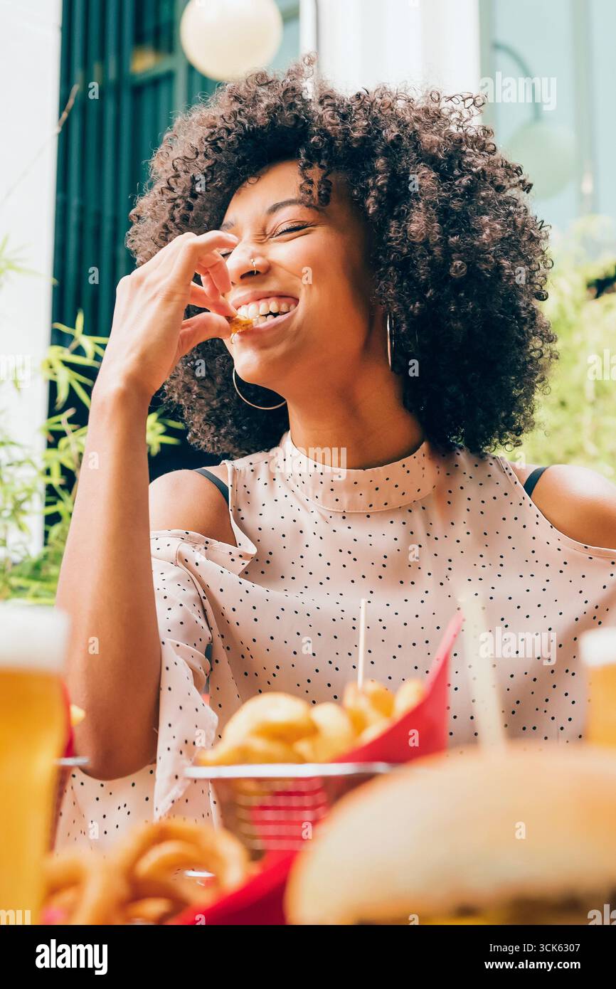 Glücklicher Gast, der Pommes frites isst und in einem Fast-Food-Restaurant lächelt Stockfoto