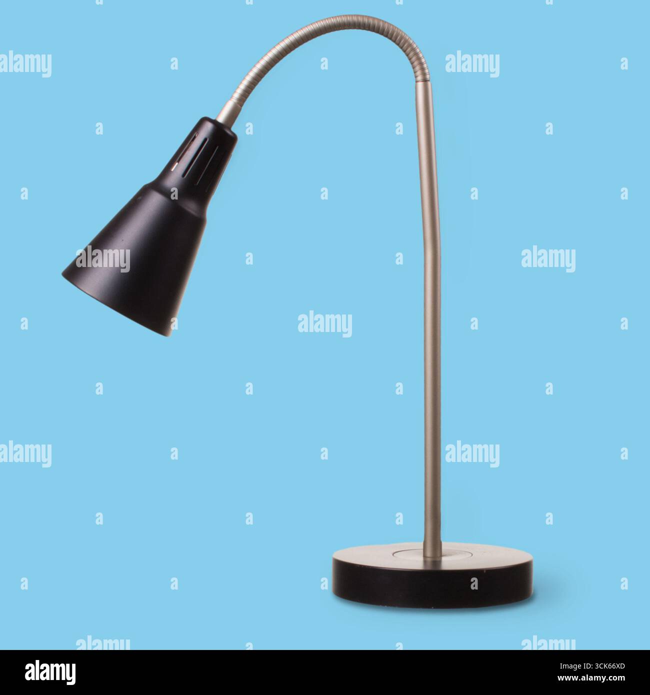 Eine schlanke Schreibtischleuchte mit flexiblem Hals und rundem Sockel, ideal für die gezielte Beleuchtung in Arbeitsbereichen. Stockfoto