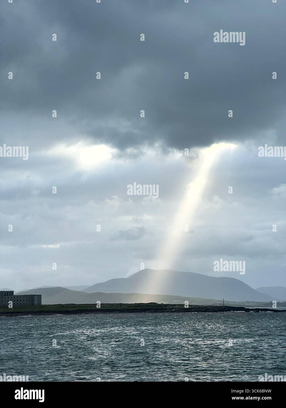Ein Schacht von Sonnenlicht, der auf einen irischen Strand fällt, Ballinskelligs Bay, County Kerry, Irland. Stockfoto