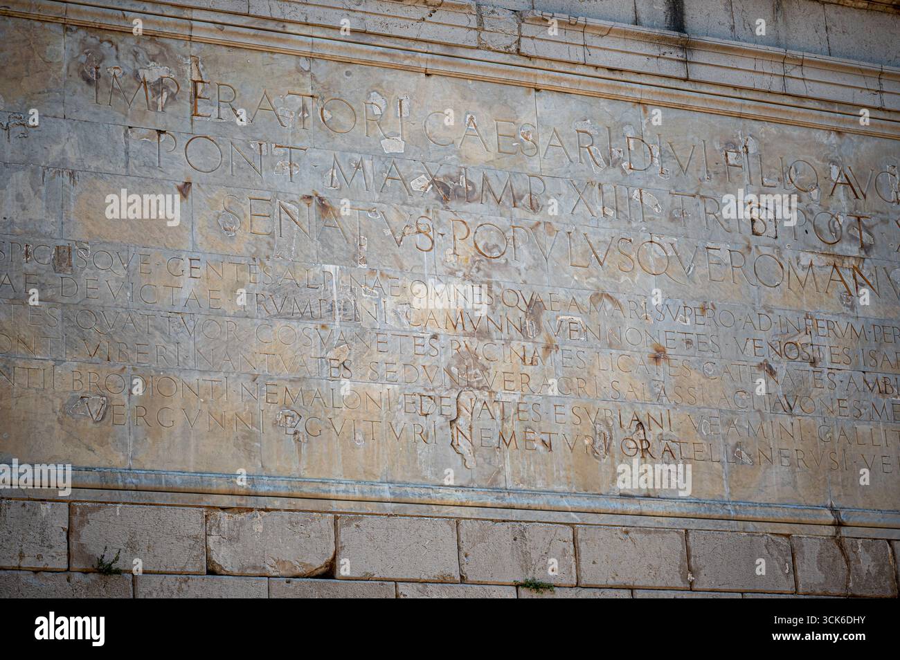 Nahaufnahme einer verwitterten lateinischen Inschrift auf der antiken römischen Trophäe der Alpen in La Turbie, Provence, Frankreich, mit geschnitzten Steindetails. Stockfoto