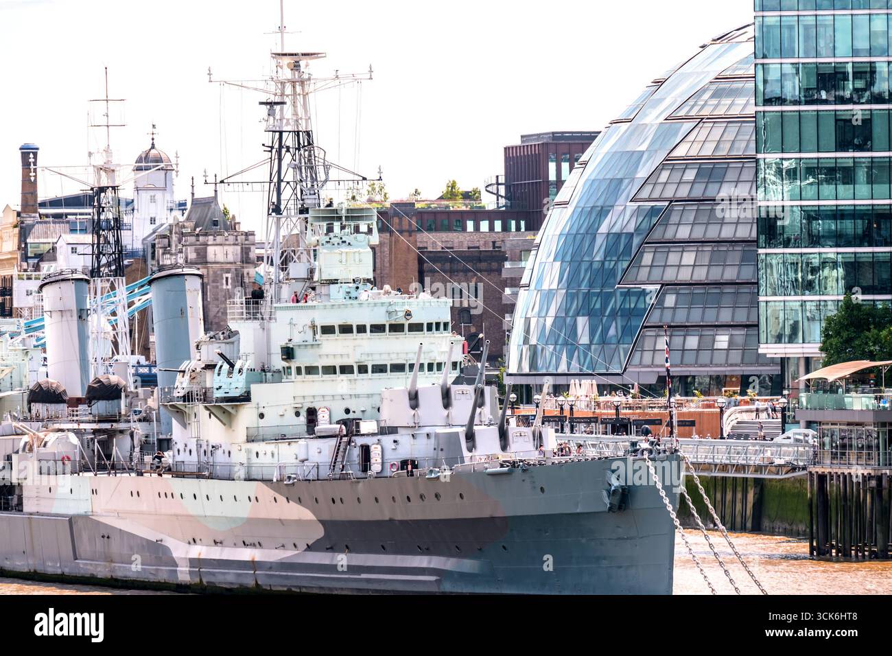 London, Großbritannien. HMS Belfast – ein leichter Kreuzer der Royal Navy (1936), der neben der Old City Hall (2002) in Southwark, der ehemaligen Heimat der London Assem, vor Anker liegt Stockfoto