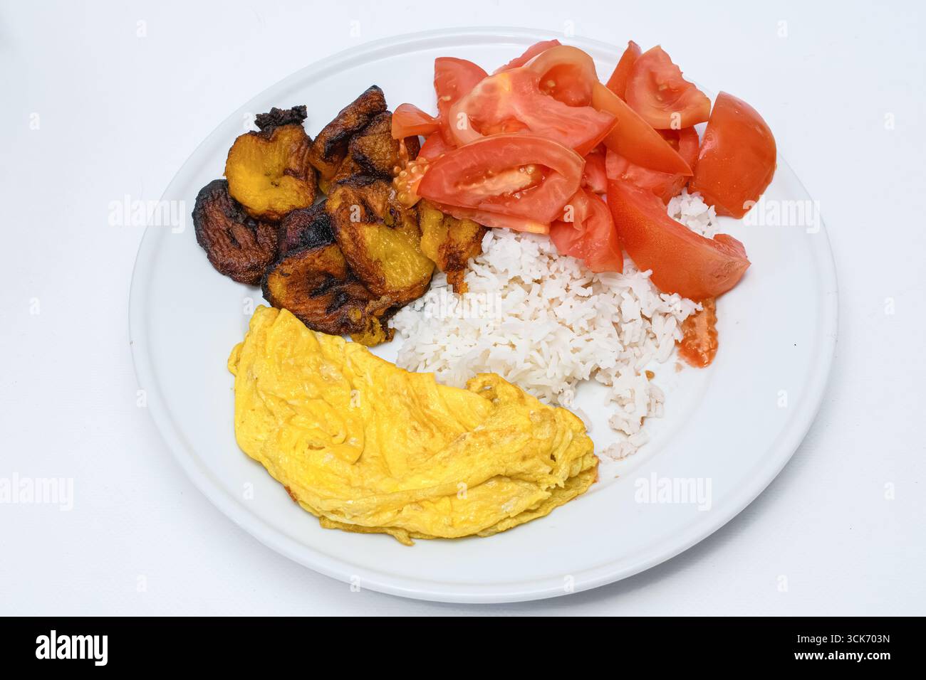 Einfaches kubanisches Essen, Reis und Bohnen, frittierte Banane, Tomatensalat und ein Eieromelett Stockfoto