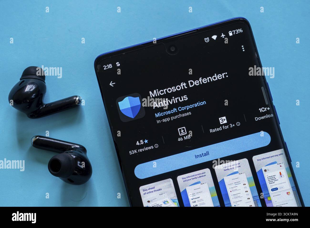 Smartphone mit Microsoft Defender Antivirus-App im Microsoft Store und schwarzen Ohrhörern Stockfoto