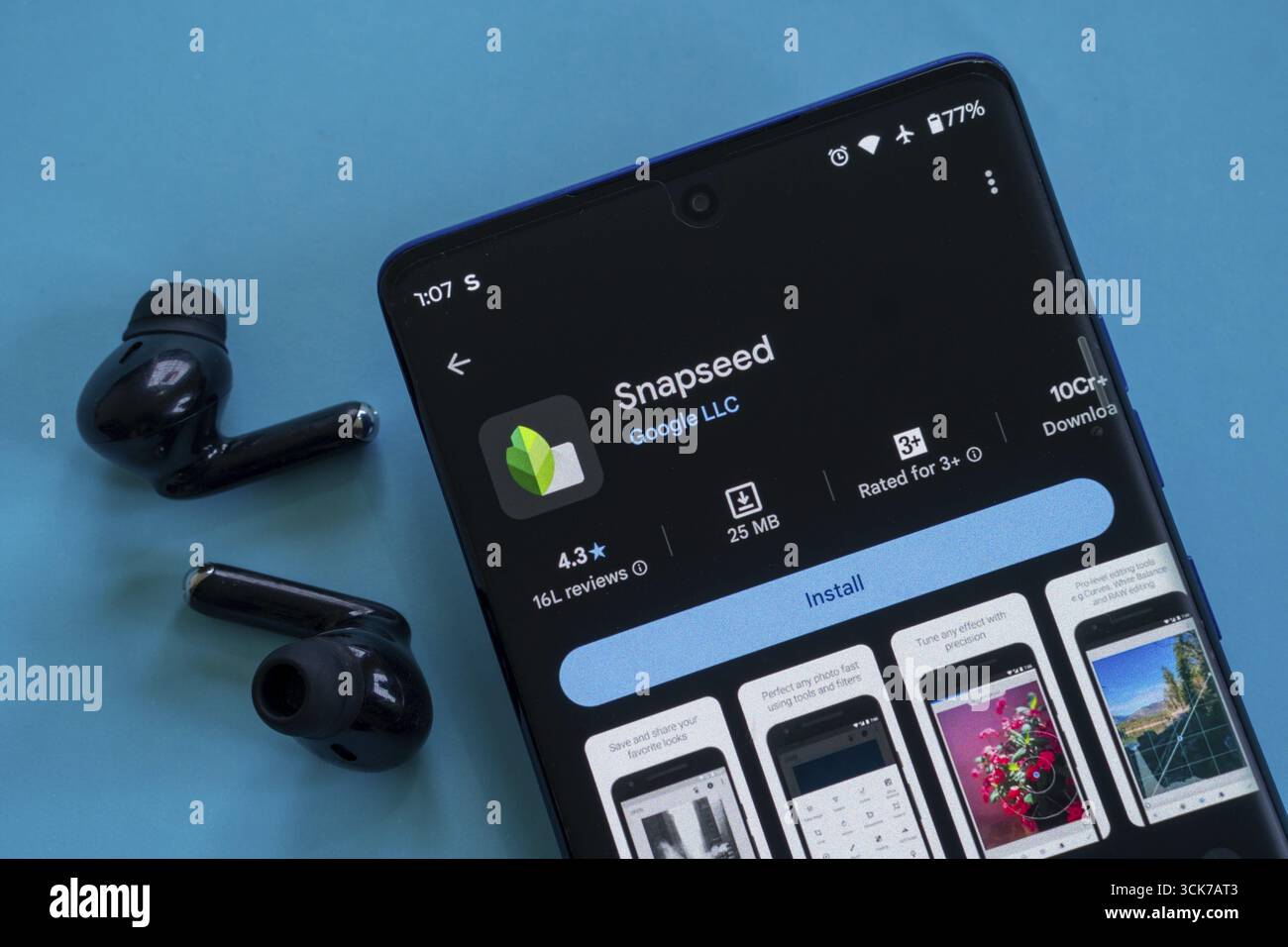 Ein Smartphone, auf dem die Snapseed App-Seite mit Installationsoption und Ohrstöpseln angezeigt wird Stockfoto