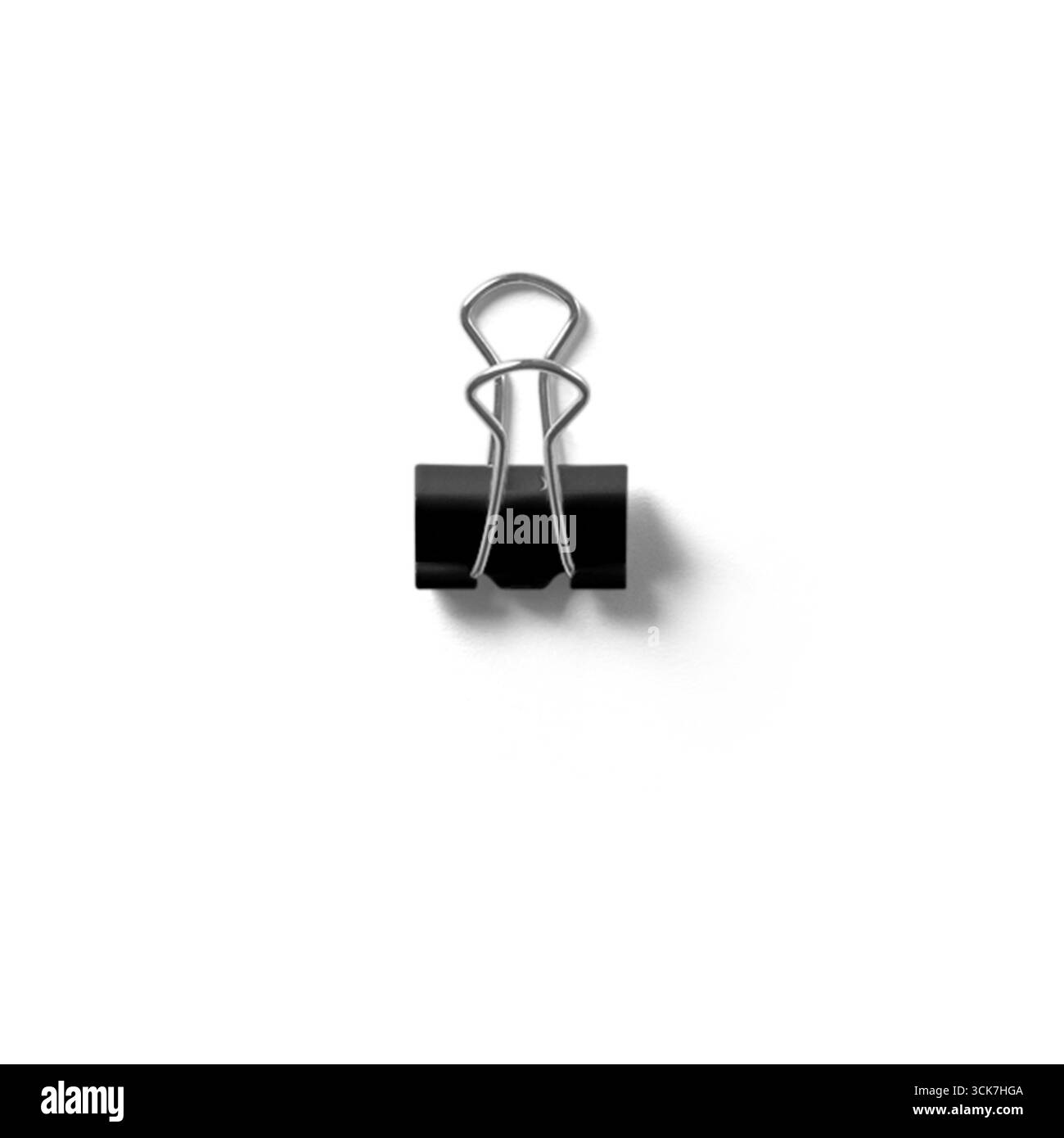 Ein schwarzer, senkrecht positionierter Binderclip, der sein Design und seine Funktionalität zum Zusammenhalten von Papieren demonstriert. Stockfoto