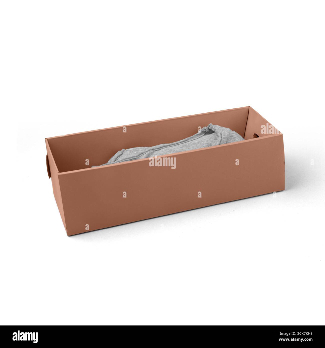 Eine rechteckige Aufbewahrungsbox in gedämpfter Farbe, die gefaltete Kleidung zur Organisation enthält. Stockfoto