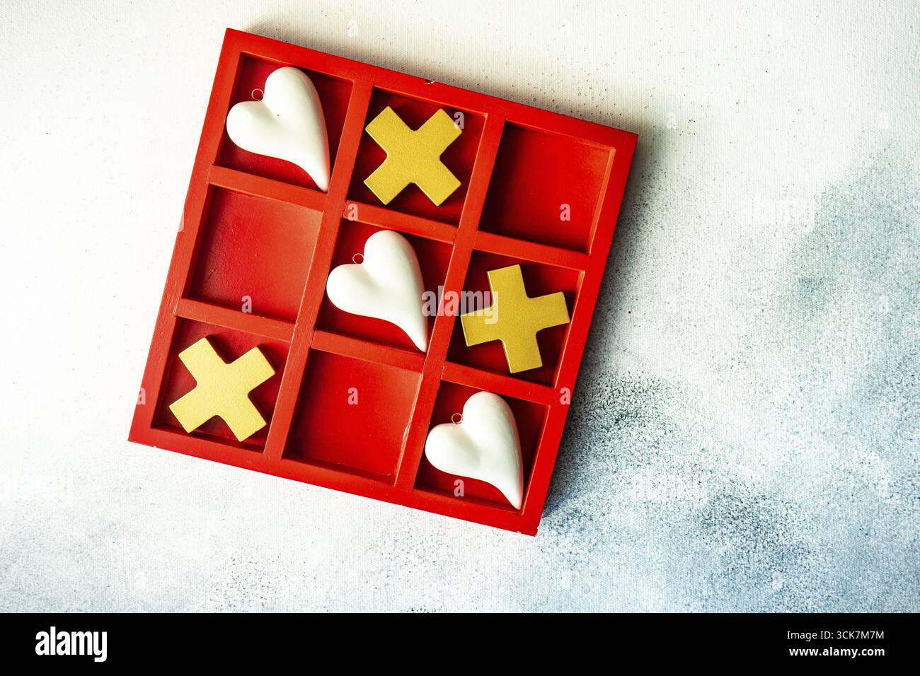 Kartenkonzept St. Valentine mit Tic-tac-Toe Brettspiel und Herzen auf steinweißem Hintergrund mit Kopierraum Stockfoto