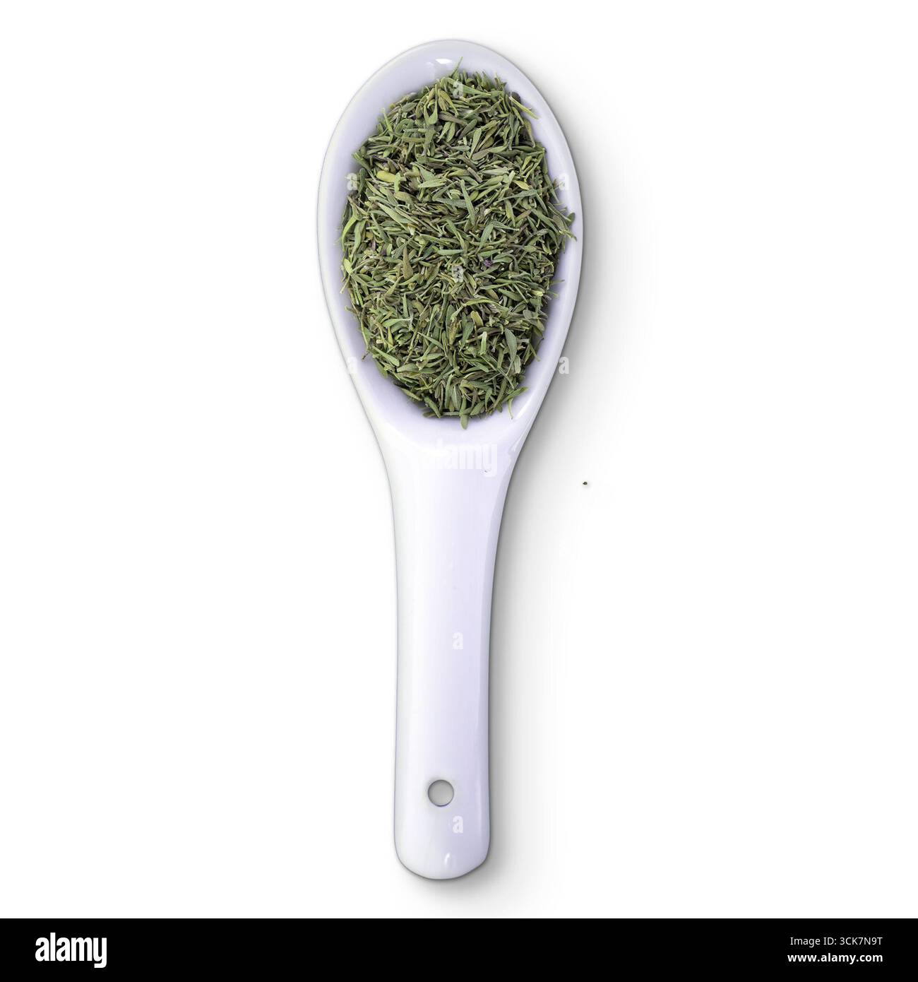 Ein weißer Löffel gefüllt mit getrockneten Kräutern, der eine kulinarische Zutat zum Kochen oder Würzen darstellt. Stockfoto