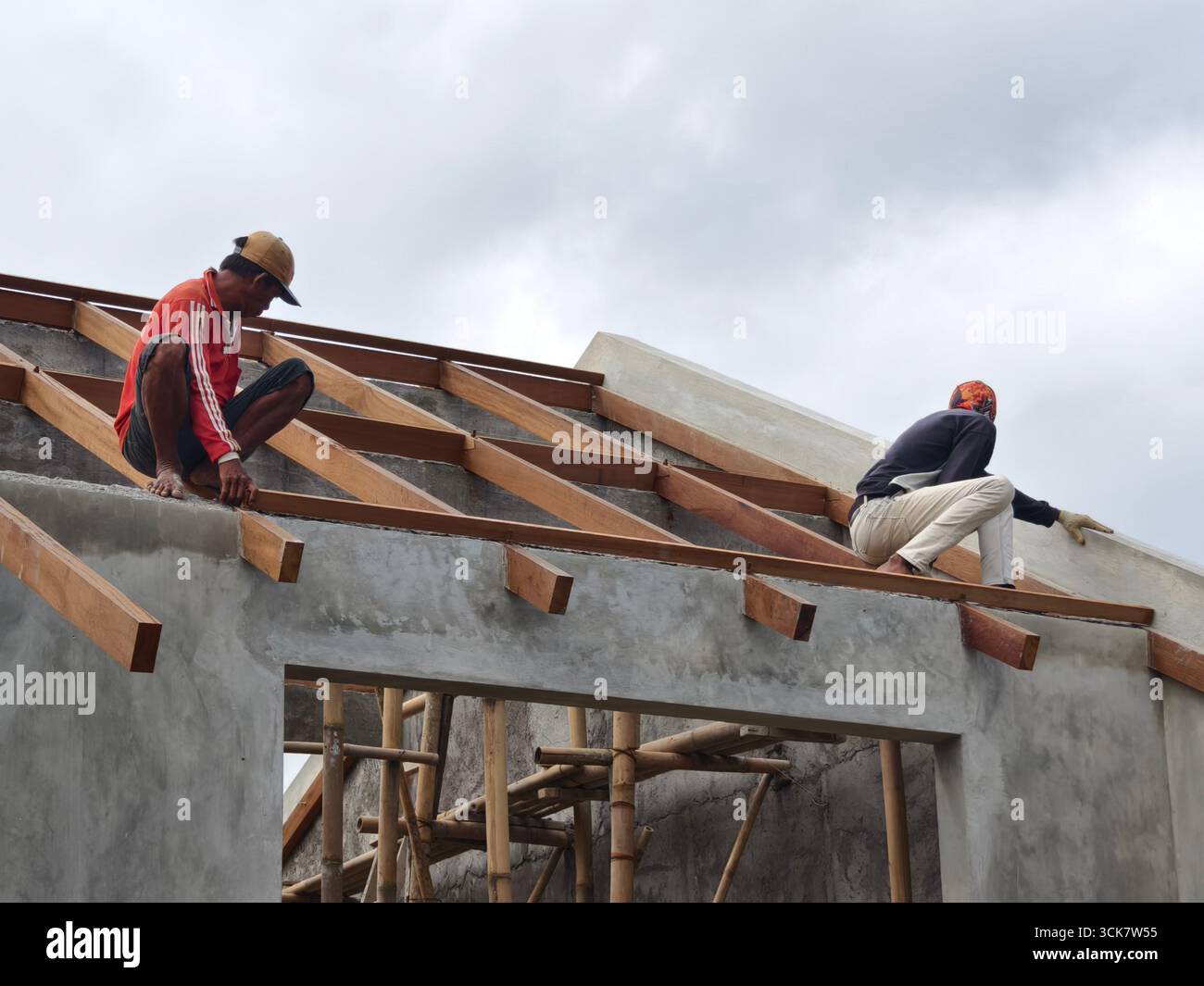 Badung, Bali, Indonesien – 5. September 2025: Bauarbeiter, die Holzdachbalken an einem im Bau befindlichen Gebäude installieren Stockfoto