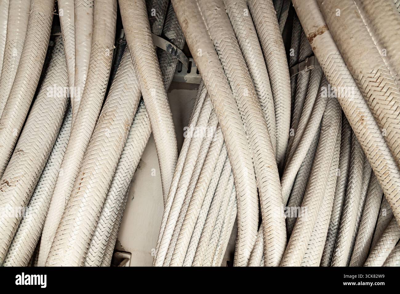 Viele dicke industrielle Elektrokabel in weißer geflochtener Isolierung, Nahaufnahme. Stockfoto