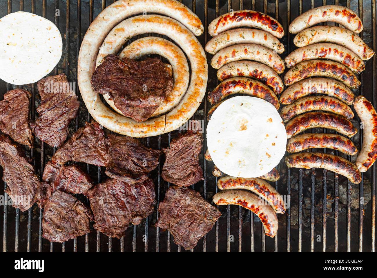 Fleischsteaks mit Würstchen und Fladenbrot drauf. Stockfoto