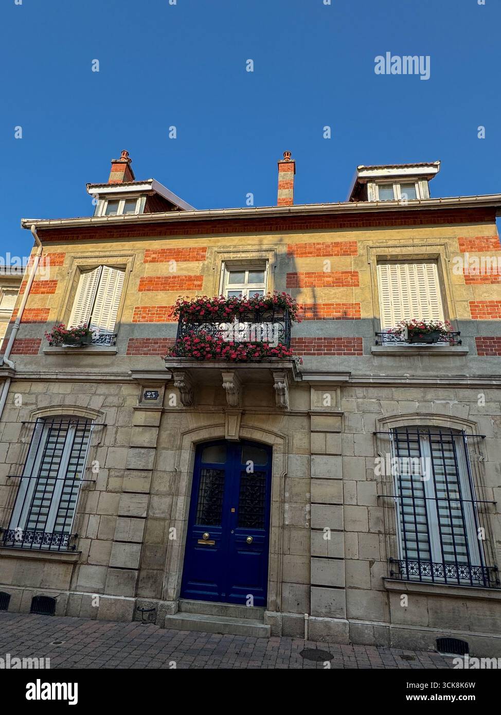 Malerische Hous in chalons en Champagne, mit beigefarbenen Steinen und roten Ziegelsteinen, schmiedeeisernem Balkon mit Blumen und einer auffälligen blauen Doppeltür Stockfoto
