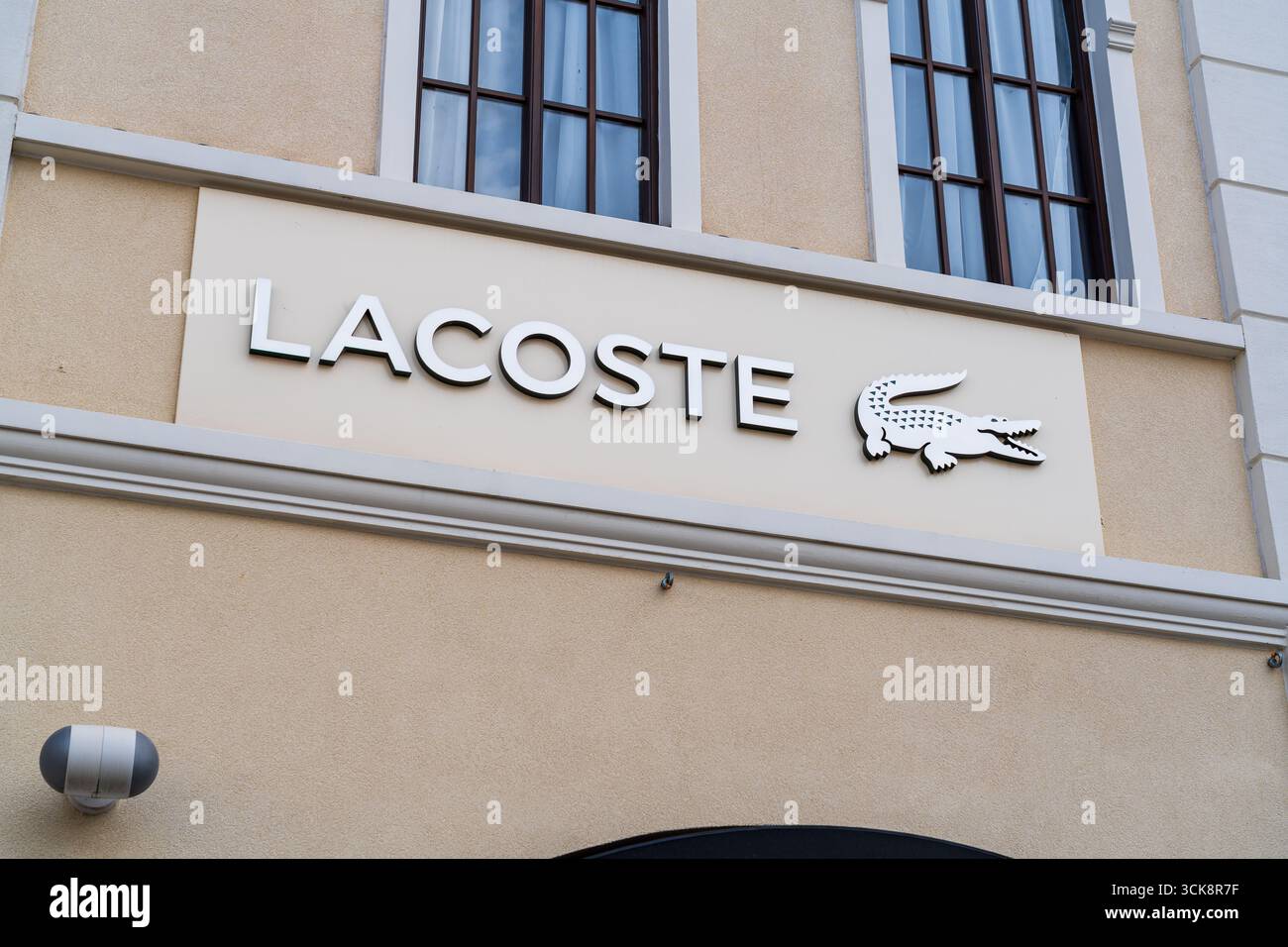 Cannock, Staffordshire, Großbritannien – 9. September 2025: Logo von Lacoste, einem weltweit tätigen Sportbekleidungsunternehmen in einem Outlet-Store Stockfoto