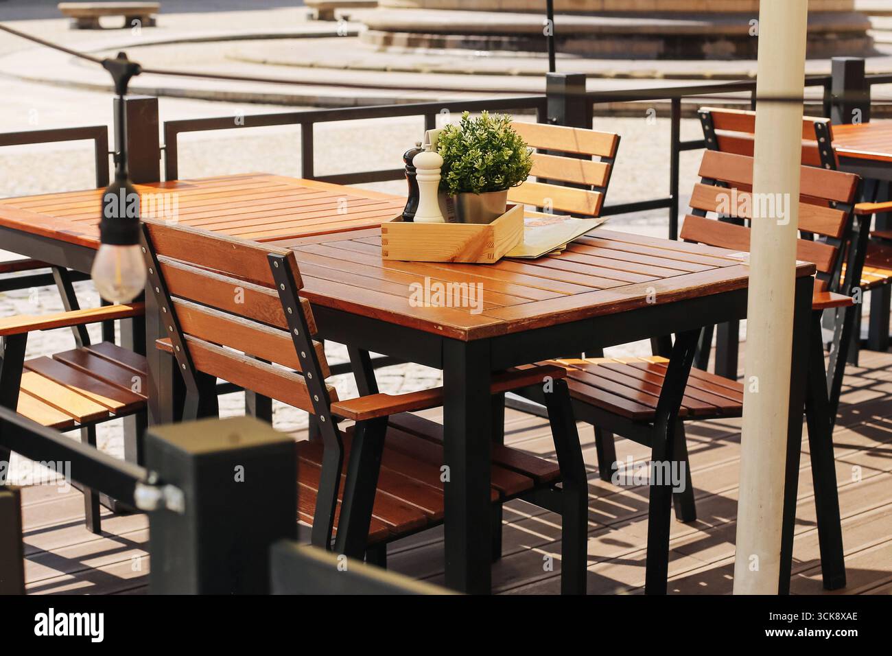 Café-Terrasse im Freien mit Holztischen. Restaurant Terrasse zum Abendessen. Moderne Möbel mit gemütlicher Atmosphäre. Entspannender Lebensstil im Freien. Stockfoto