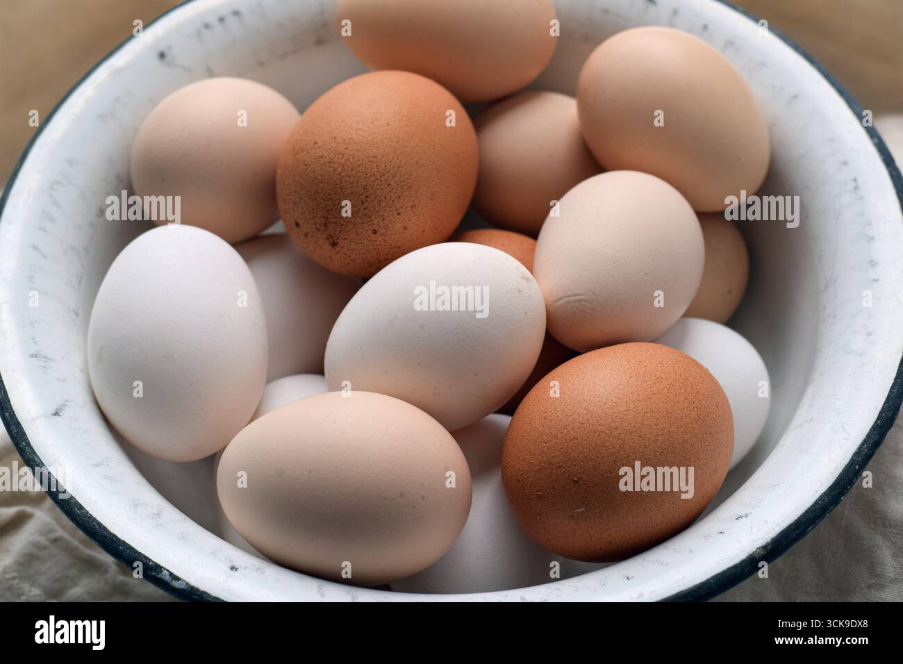 Nahaufnahme von oben nach unten mit verschiedenen Hühnereiern in verschiedenen Farben, die in einer Vintage-Emaille-Schüssel platziert sind. Farm Fresh, rustikales und biologisches Konzept Stockfoto