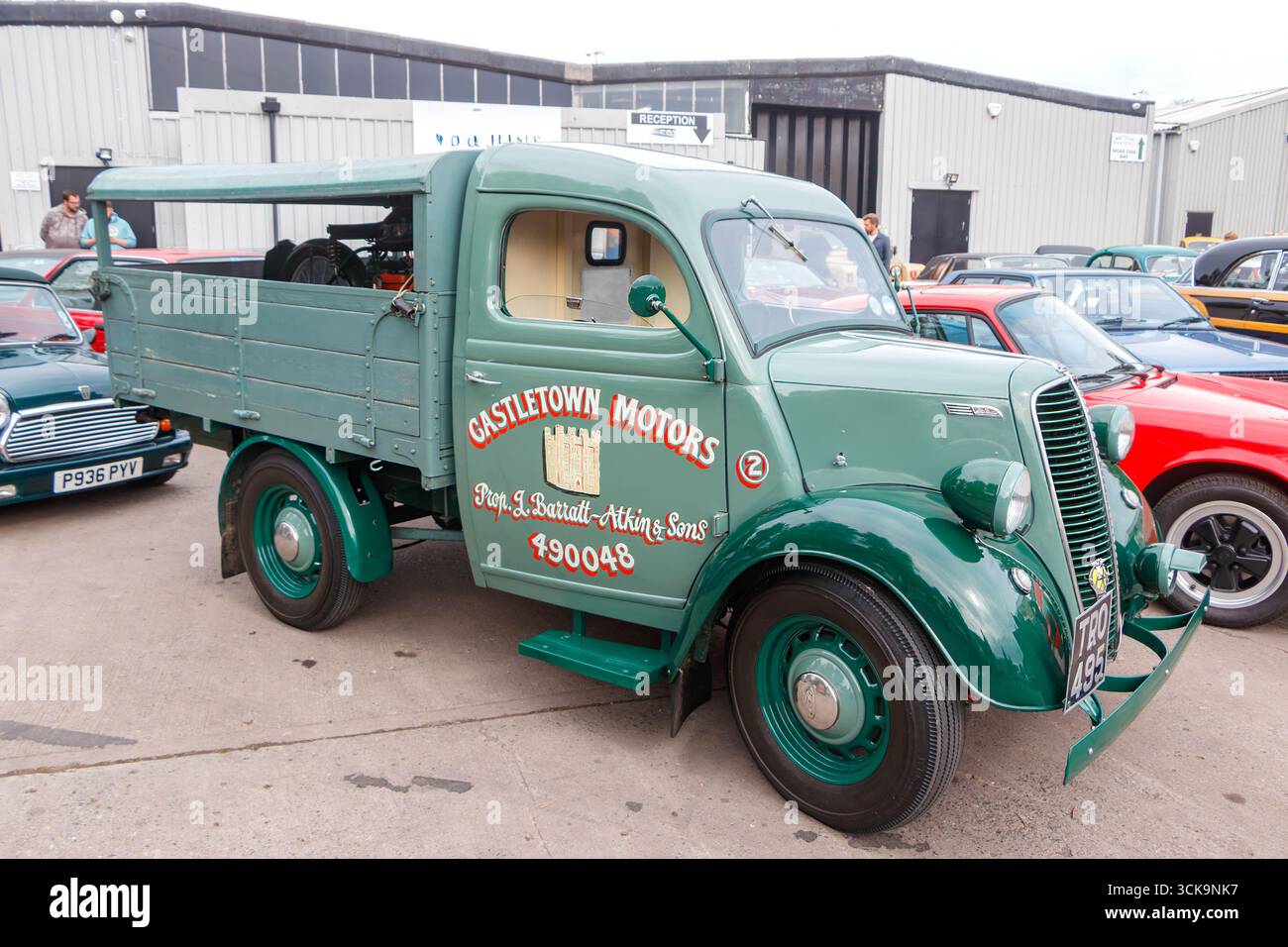 Grüner Ford Thames E83W Lieferwagen mit Castletown Motors Branding, der in Oldtimern vor einer Garage geparkt ist Stockfoto