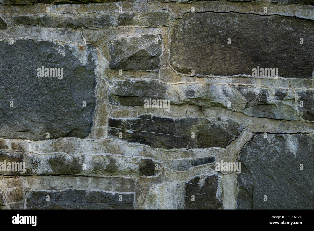 Nahaufnahme einer verwitterten Steinwand mit natürlichen Rissen und veralteter Textur. Stockfoto