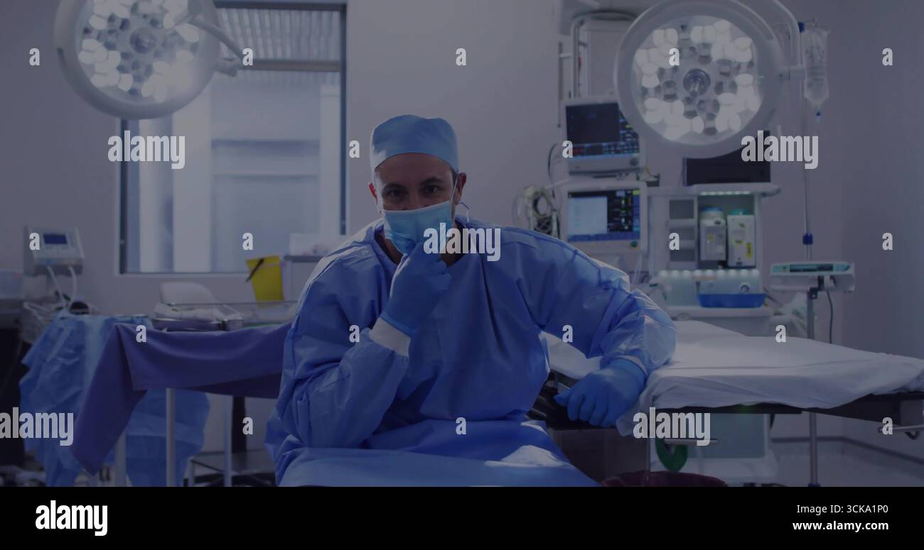 Sitzender Chirurg in chirurgischer Kleidung, Beobachtermonitore im Operationssaal, mit Deckenleuchten Stockfoto