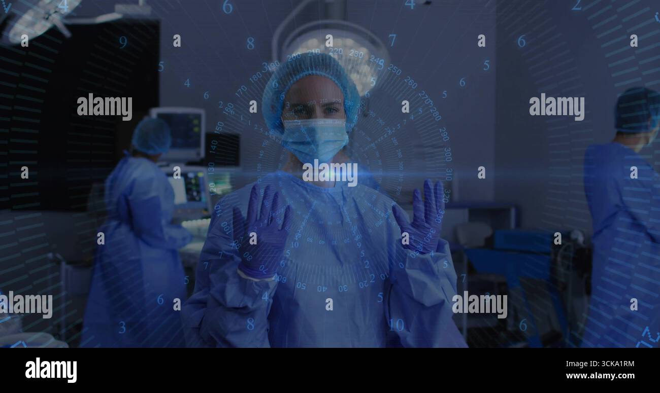 Stehender Chirurg und Assistenzteam im OP, mit Operationslampen, Monitoren Stockfoto