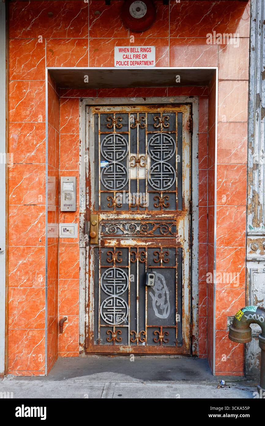 Ein rostiges Metalltor mit orientalisch-asiatischen Designelementen, eingerahmt von einem orangen Fliesentor. Stockfoto