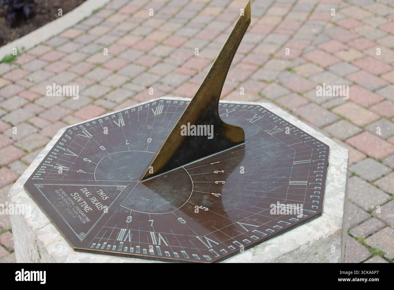 Sonnenuhr aus Nahaufnahme auf Betonsockel über der Terrasse aus Pflasterstein Stockfoto
