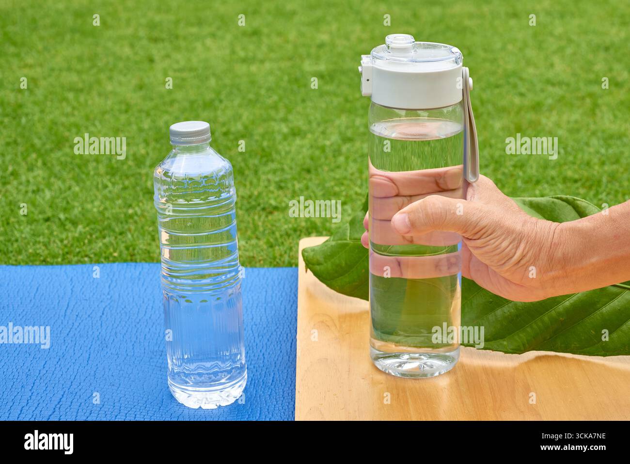 Die Hand einer Person greift nach einer wiederverwendbaren Flasche anstelle einer Einwegflasche aus Plastik. Ein leistungsfähiges Konzept für Nachhaltigkeit, das die Kunststoffproduktion reduziert Stockfoto