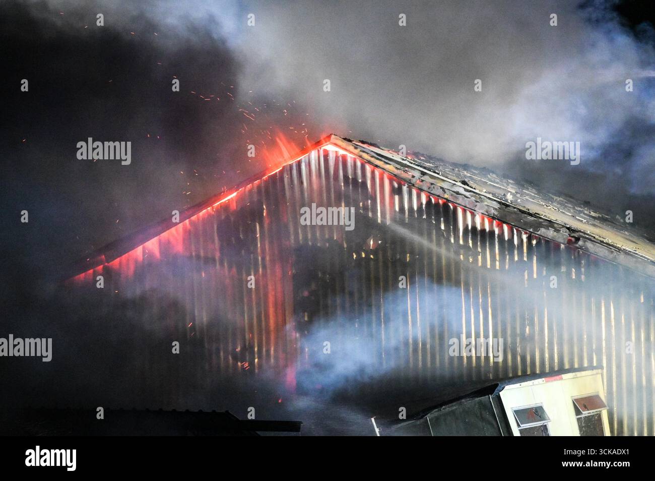 Longbridge, Birmingham, 11. September 2025. Mehr als 60 Feuerwehrleute sind in den frühen Morgenstunden des Donnerstags bei einem großen Brand in Longbridge, Birmingham, anwesend. Die Flamme hat Frankley Tyre Lagerhaus auf dem alten Gelände des MG Rover West Works erobert. Zwölf Feuerwehrfahrzeuge, zwei hydraulische Plattformen, die Vorfallskommando und verschiedene andere Ressourcen der Polizei, Cadent und des National Grid waren anwesend. Flammen leckten das Gebäude ab, als Wände einstürzten und die Feuerwehr Wasser mit Schläuchen besprühte. Die West Midlands Fire Service sagte in einem Beitrag auf Facebook: „Wir haben 12 Mannschaften, die bei einem Brand auf W anwesend sind Stockfoto