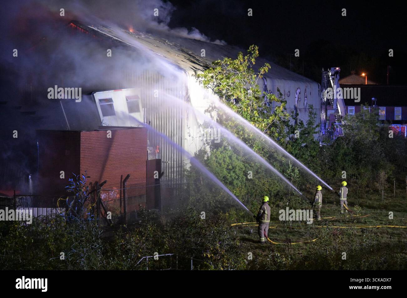 Longbridge, Birmingham, 11. September 2025. Mehr als 60 Feuerwehrleute sind in den frühen Morgenstunden des Donnerstags bei einem großen Brand in Longbridge, Birmingham, anwesend. Die Flamme hat Frankley Tyre Lagerhaus auf dem alten Gelände des MG Rover West Works erobert. Zwölf Feuerwehrfahrzeuge, zwei hydraulische Plattformen, die Vorfallskommando und verschiedene andere Ressourcen der Polizei, Cadent und des National Grid waren anwesend. Flammen leckten das Gebäude ab, als Wände einstürzten und die Feuerwehr Wasser mit Schläuchen besprühte. Die West Midlands Fire Service sagte in einem Beitrag auf Facebook: „Wir haben 12 Mannschaften, die bei einem Brand auf W anwesend sind Stockfoto