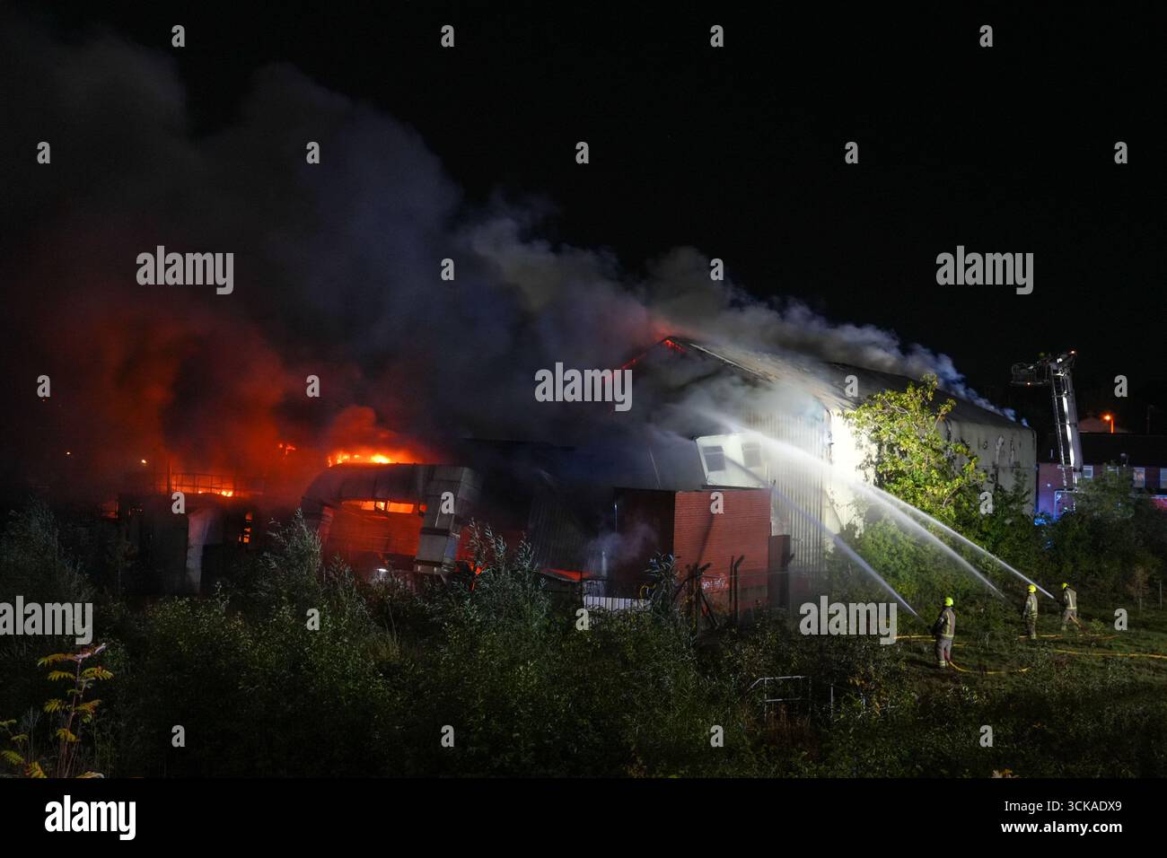Longbridge, Birmingham, 11. September 2025. Mehr als 60 Feuerwehrleute sind in den frühen Morgenstunden des Donnerstags bei einem großen Brand in Longbridge, Birmingham, anwesend. Die Flamme hat Frankley Tyre Lagerhaus auf dem alten Gelände des MG Rover West Works erobert. Zwölf Feuerwehrfahrzeuge, zwei hydraulische Plattformen, die Vorfallskommando und verschiedene andere Ressourcen der Polizei, Cadent und des National Grid waren anwesend. Flammen leckten das Gebäude ab, als Wände einstürzten und die Feuerwehr Wasser mit Schläuchen besprühte. Die West Midlands Fire Service sagte in einem Beitrag auf Facebook: „Wir haben 12 Mannschaften, die bei einem Brand auf W anwesend sind Stockfoto